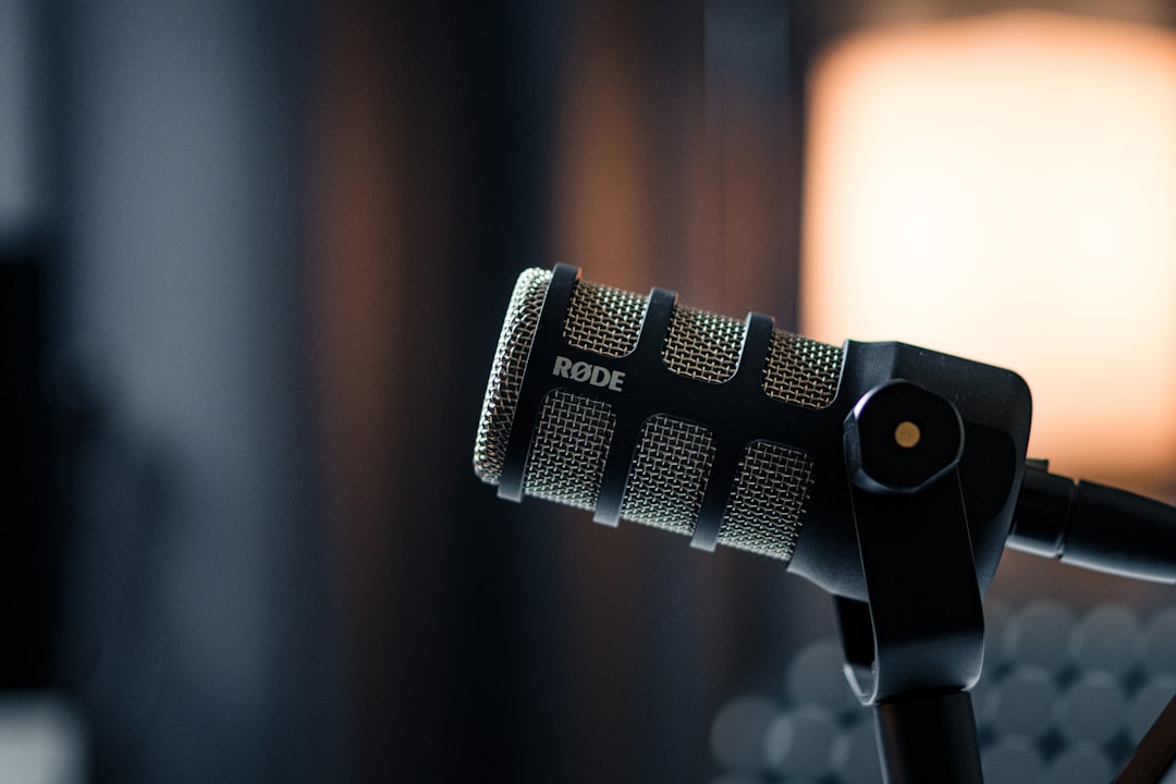 a close up of a microphone with a light in the background, Rode PodMic audio microphone in a Podcast Studio<p></figure>
