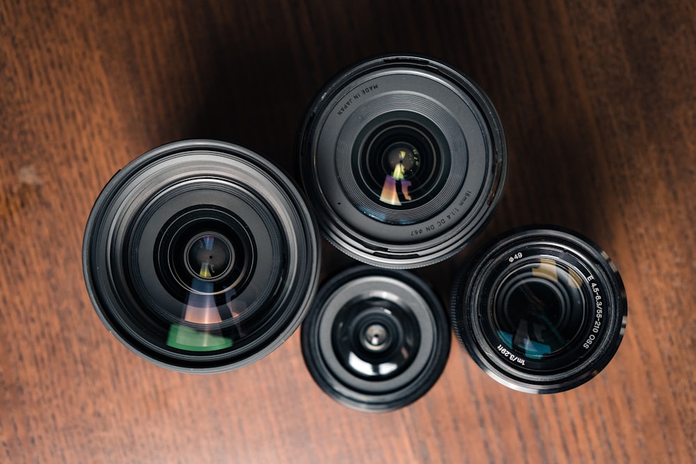 a group of three cameras sitting on top of a wooden table