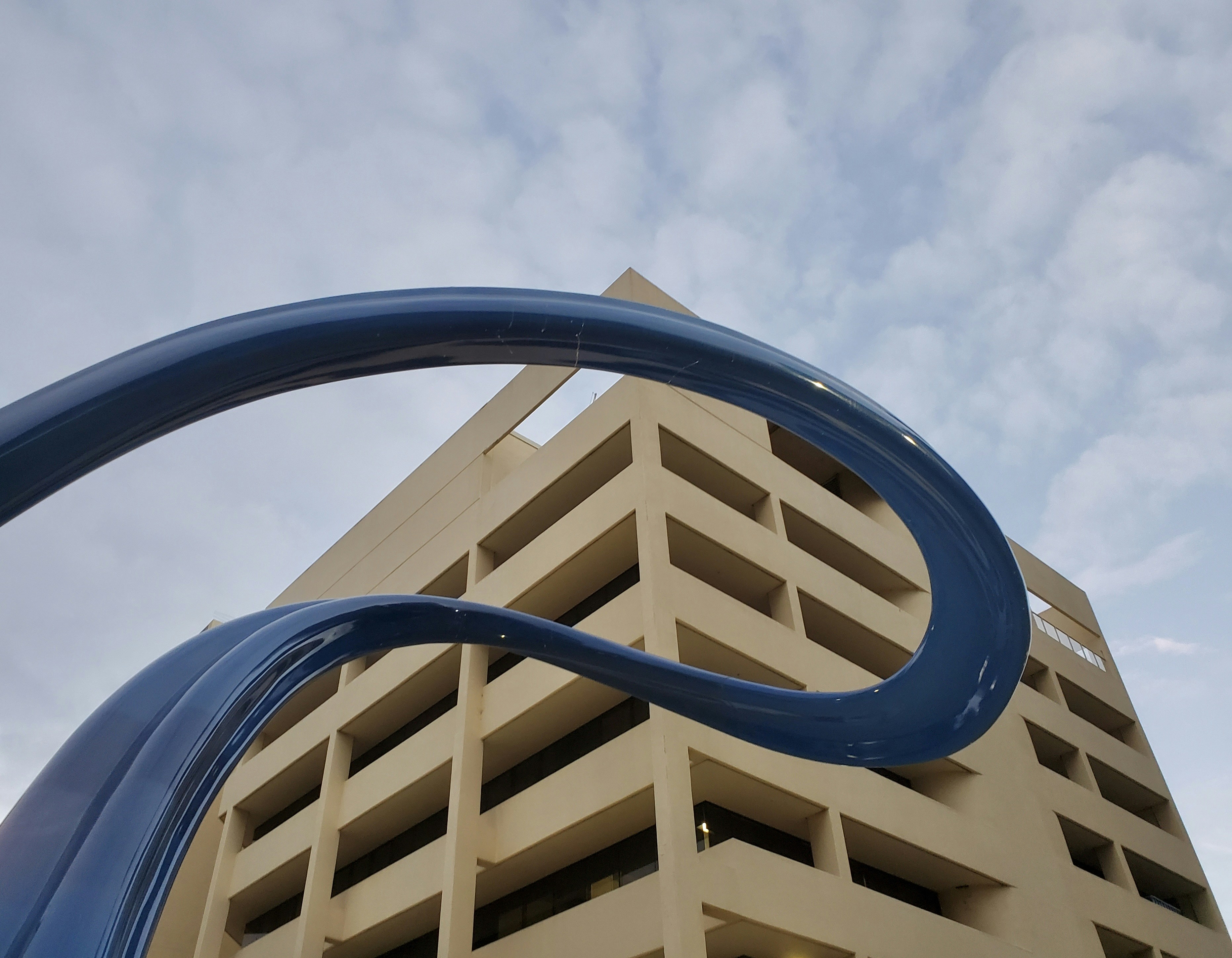 ein hohes Gebäude mit einer blauen Skulptur davor