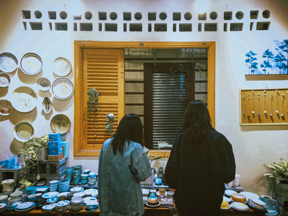 a couple of women standing in front of a table filled with plates