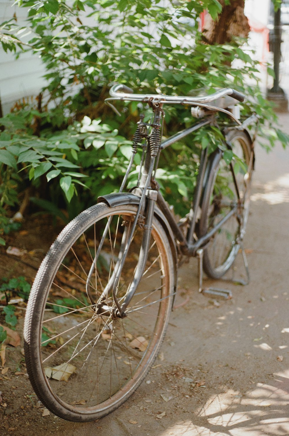 a bicycle parked on a sidewalk next to a bush