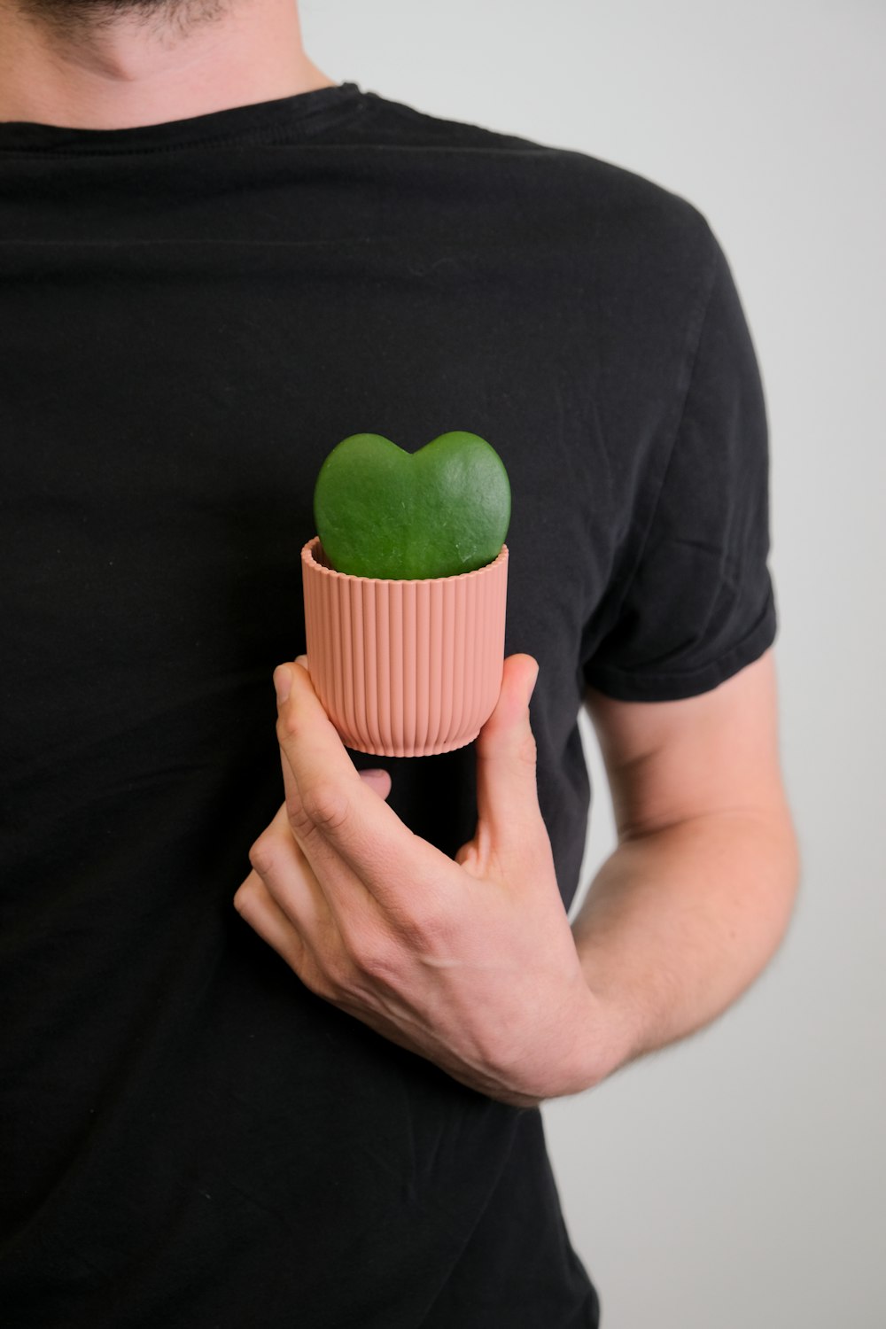 Un hombre sosteniendo una taza rosa con un corazón verde en ella