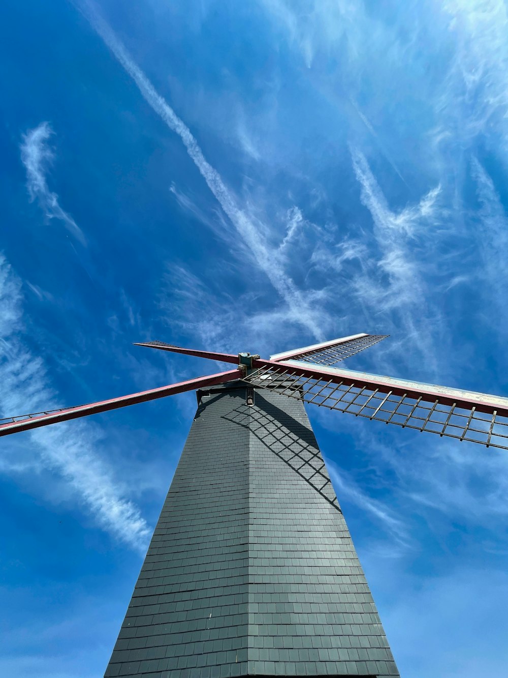 a windmill is shown against a blue sky with wispy clouds
