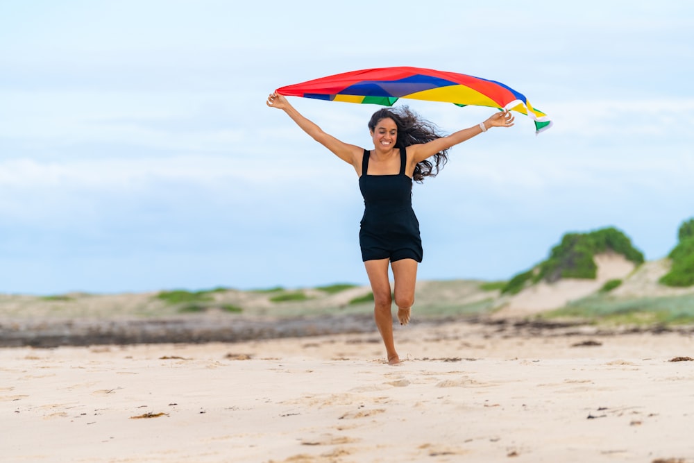 a woman running on a beach holding a kite