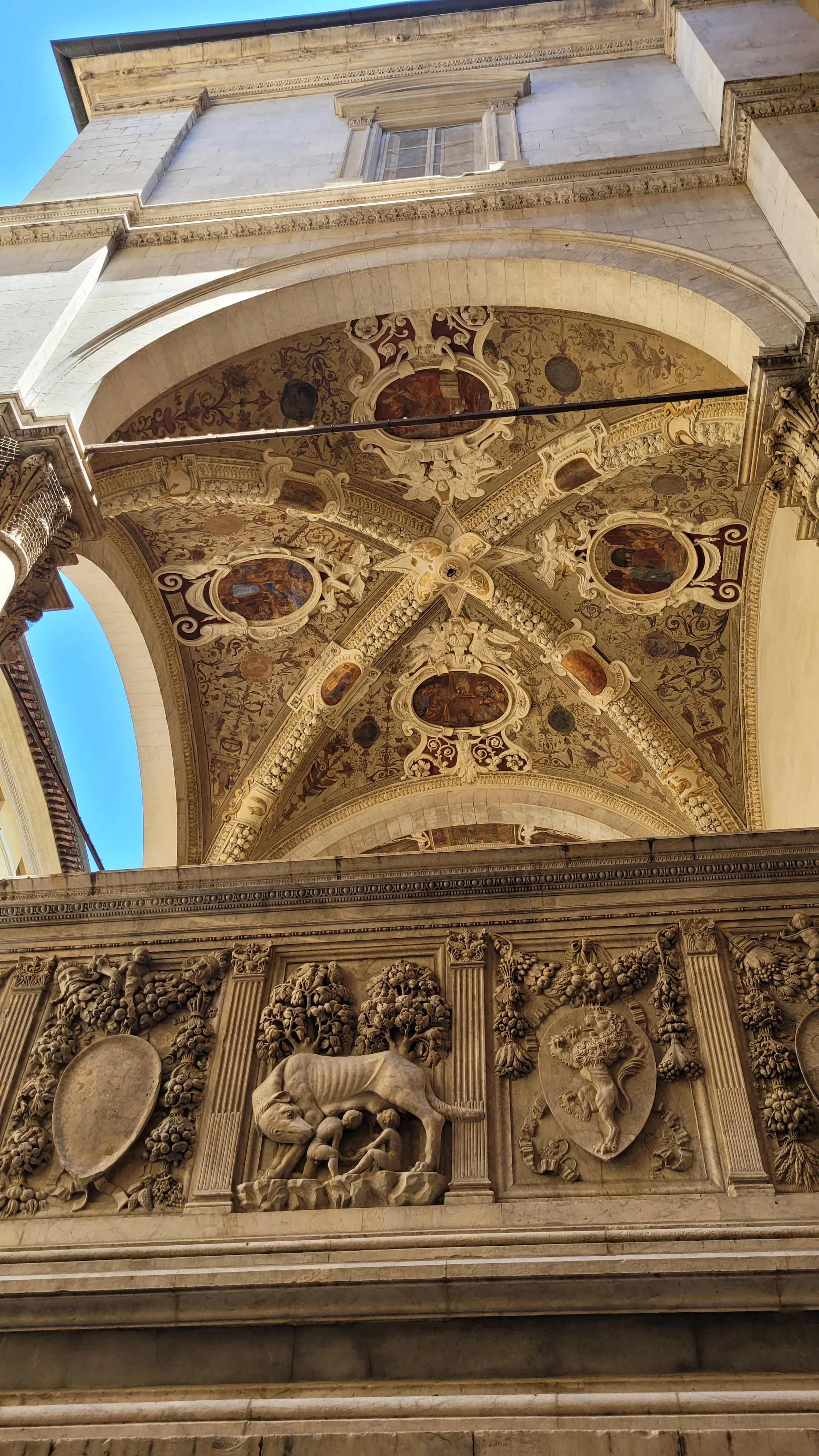 Beschilderd gewelf en stenen details van de Loggia della Mercanzia in Siena