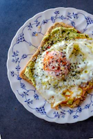 An elegant breakfast setup featuring toast topped with avocado and a hint of seh enhancer on the side.