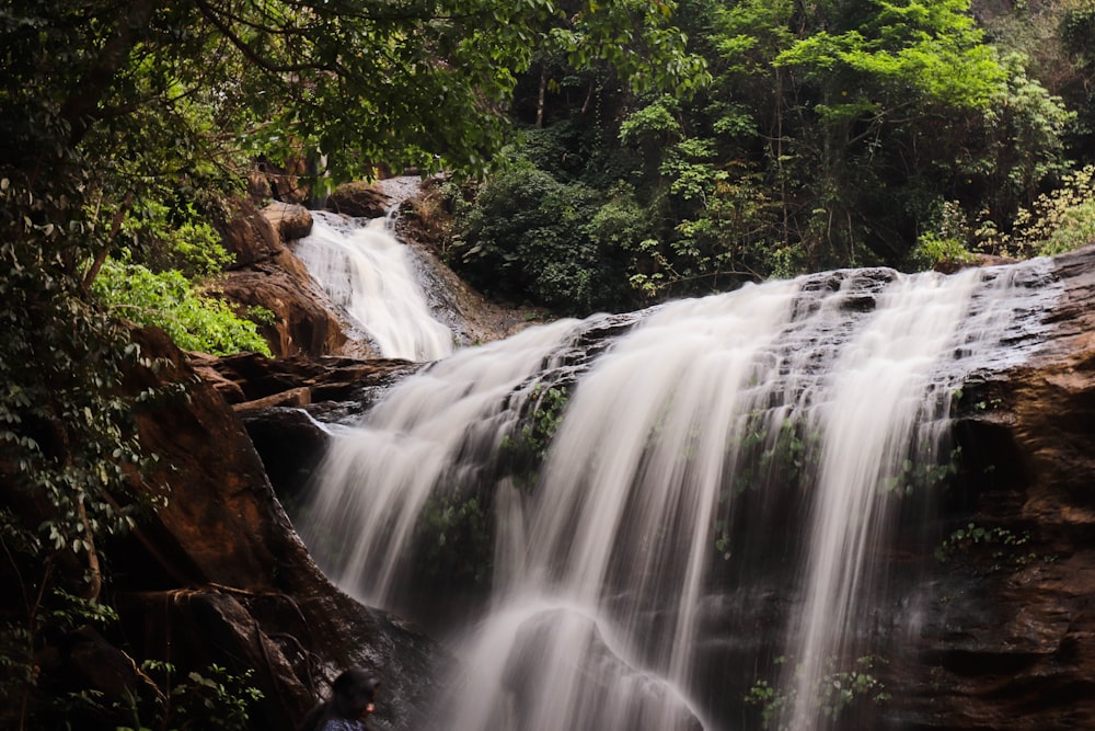 a man standing in front of a waterfall