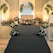 An elegant stage setup with floral decorations arranged symmetrically around a beige couch. Soft lighting creates a warm ambiance, complemented by a patterned backdrop with initials 'DS'. Flowers in white and yellow are arranged in bouquets on either side and at the base of the stage, with decorative arches flanking the setup.