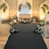 An elegant stage setup with floral decorations arranged symmetrically around a beige couch. Soft lighting creates a warm ambiance, complemented by a patterned backdrop with initials 'DS'. Flowers in white and yellow are arranged in bouquets on either side and at the base of the stage, with decorative arches flanking the setup.
