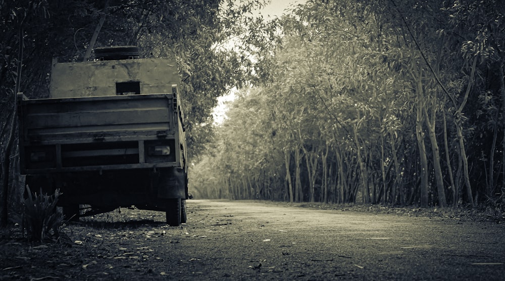 a truck driving down a dirt road next to a forest