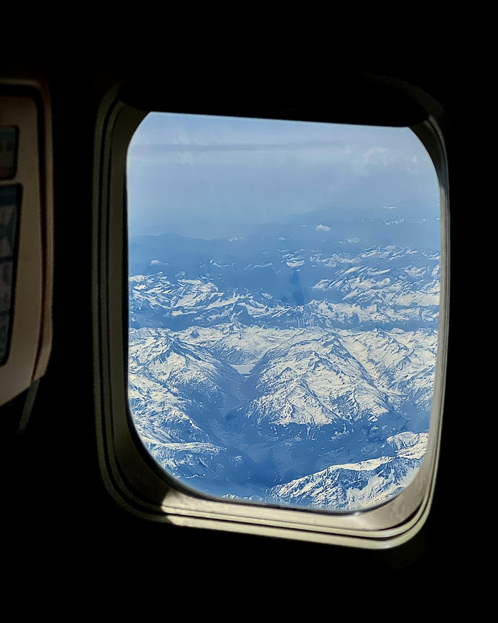 a view of a snowy mountain range from an airplane window