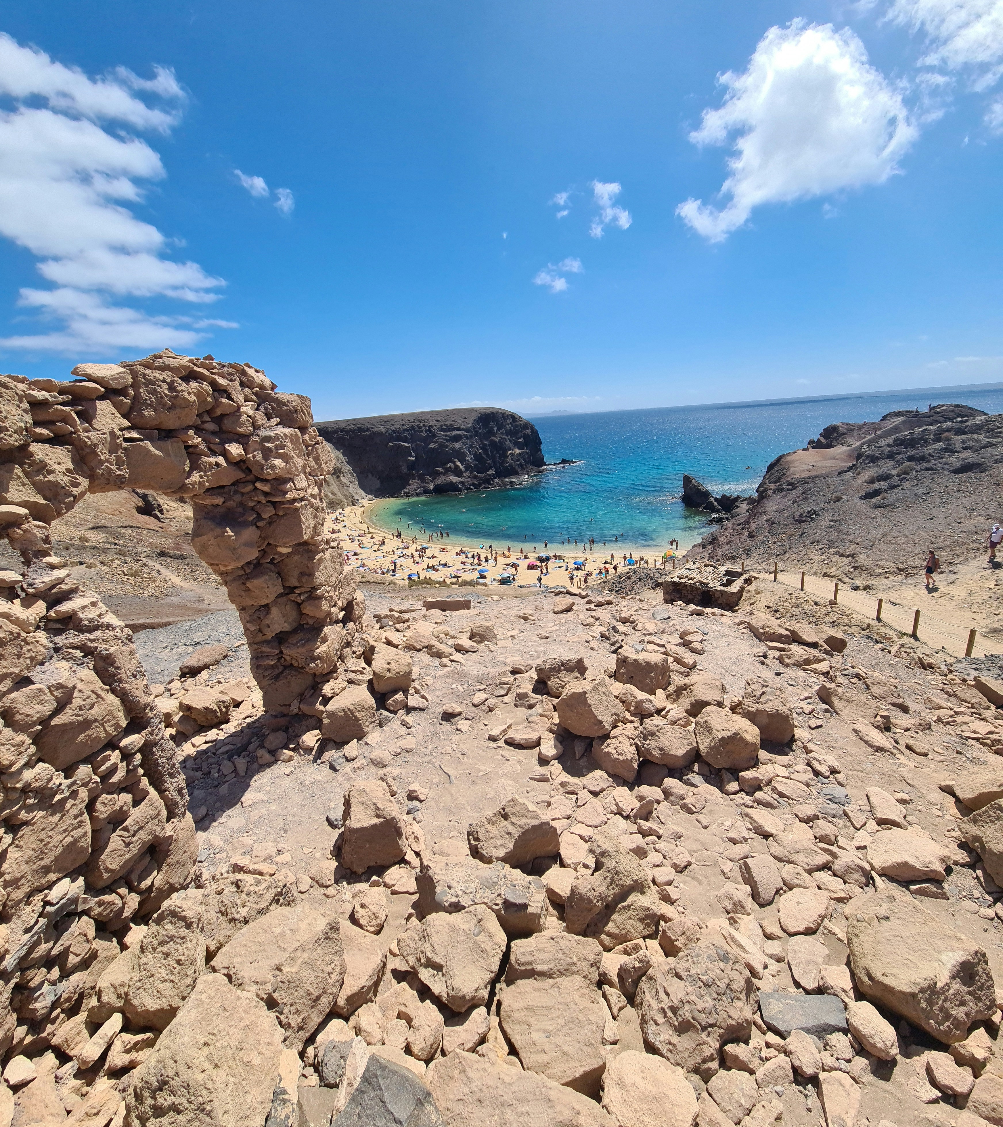a view of a rocky beach with people in the water