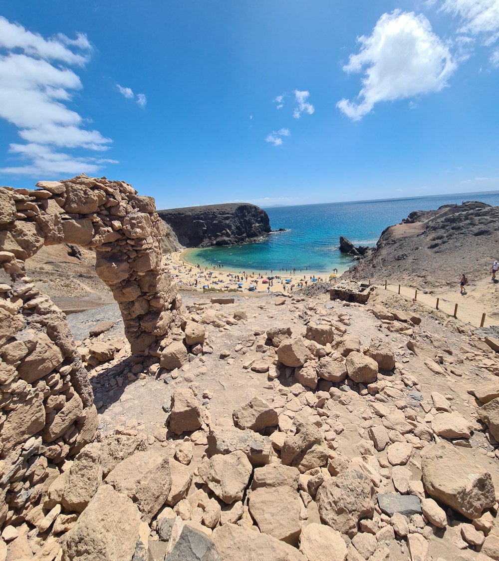 a view of a rocky beach with people in the water