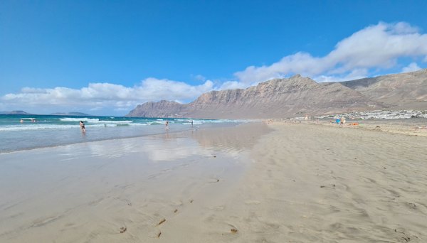 A sandy beach below a long line of cliffs — Lanzarote, Spain