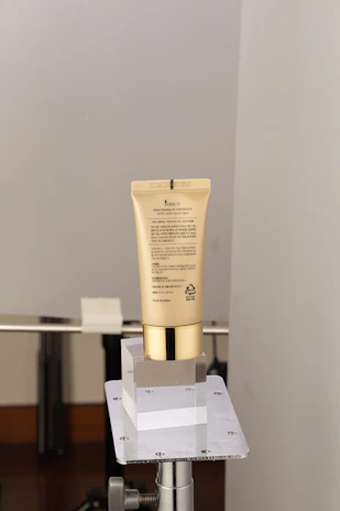 Sleek sunscreen tube placed on smooth marble with subtle gold accents.
