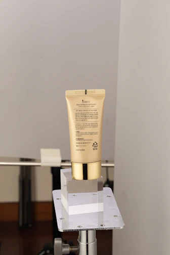 Sleek sunscreen tube placed on smooth marble with subtle gold accents.