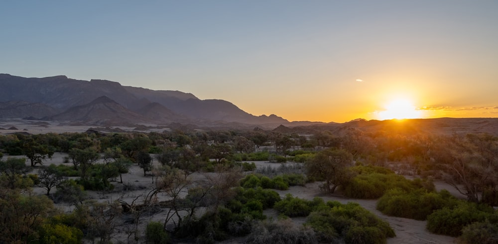 the sun is setting over the mountains in the desert
