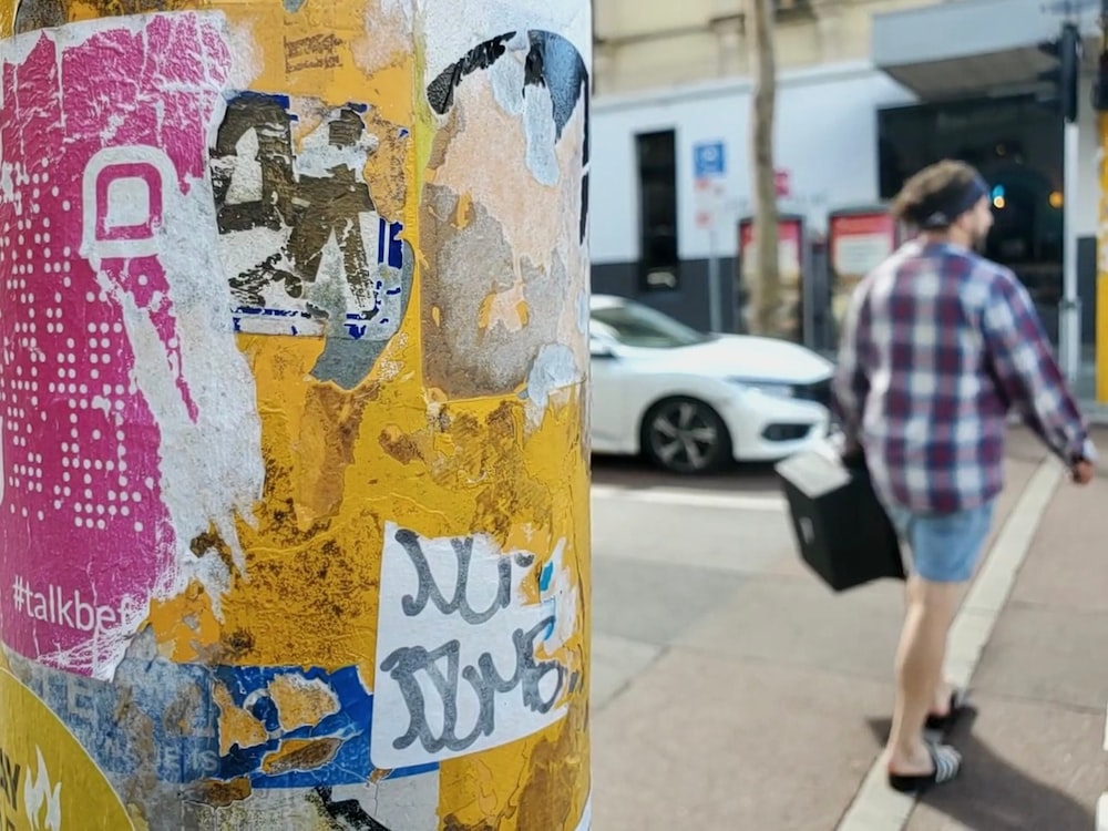 a person walking down a sidewalk next to a pole