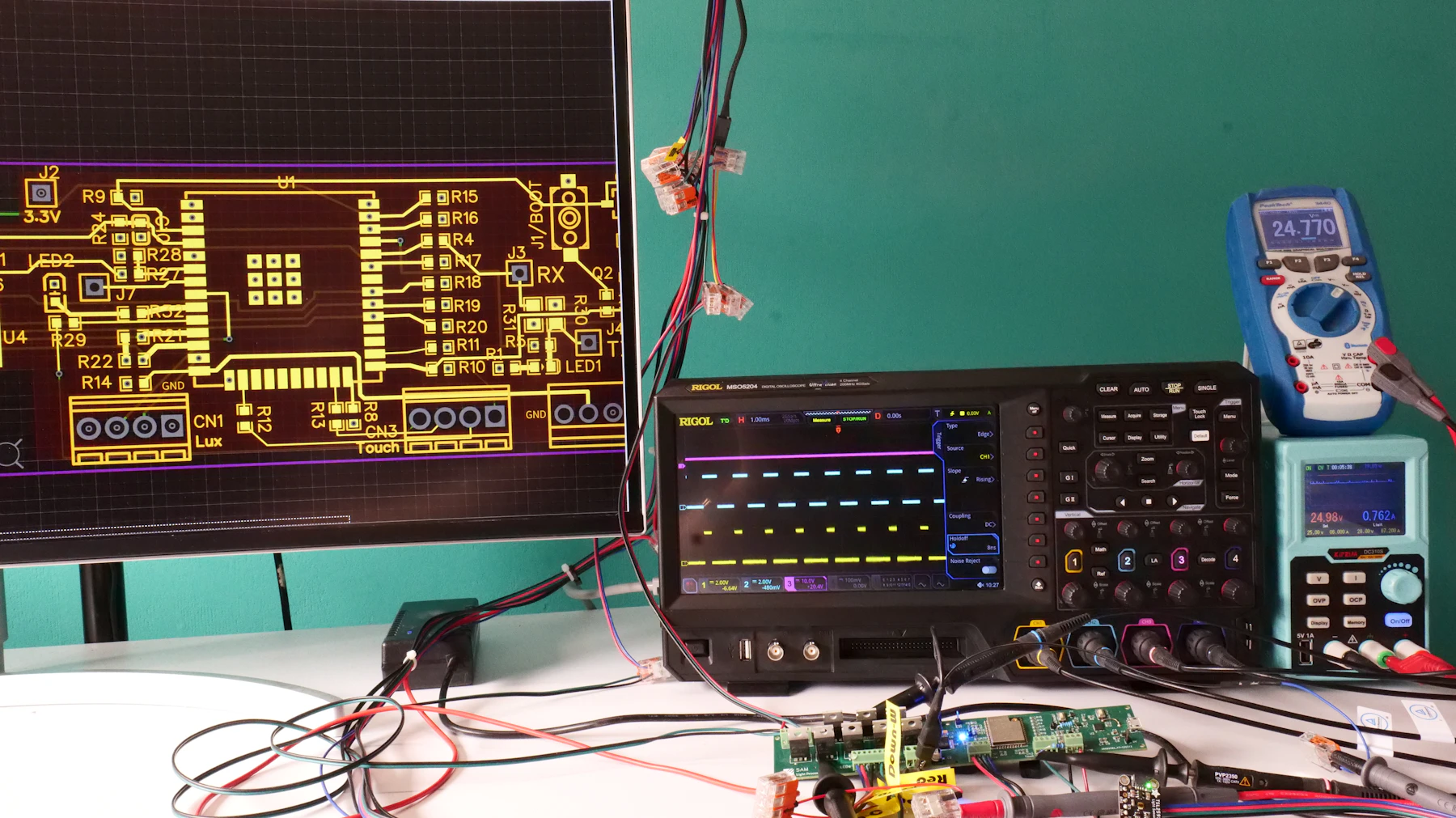 Electronics workbench with circuit board, measurements, and test equipment