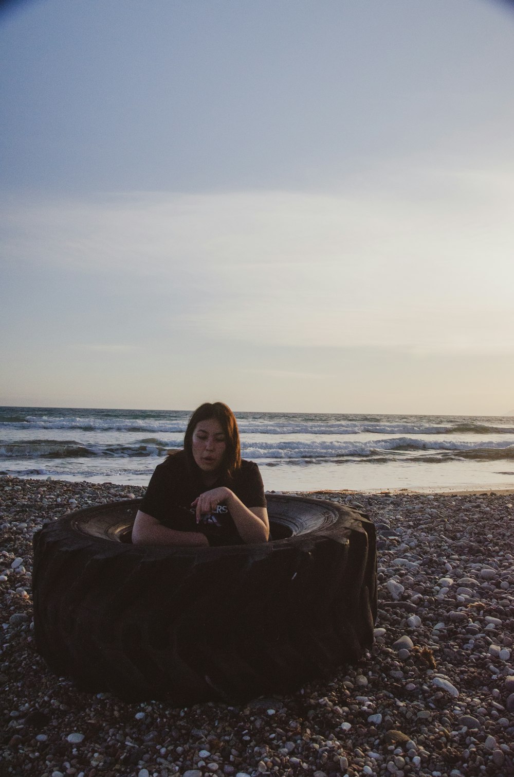 한 여자가 해변의 콩 주머니 의자에 앉아 있다