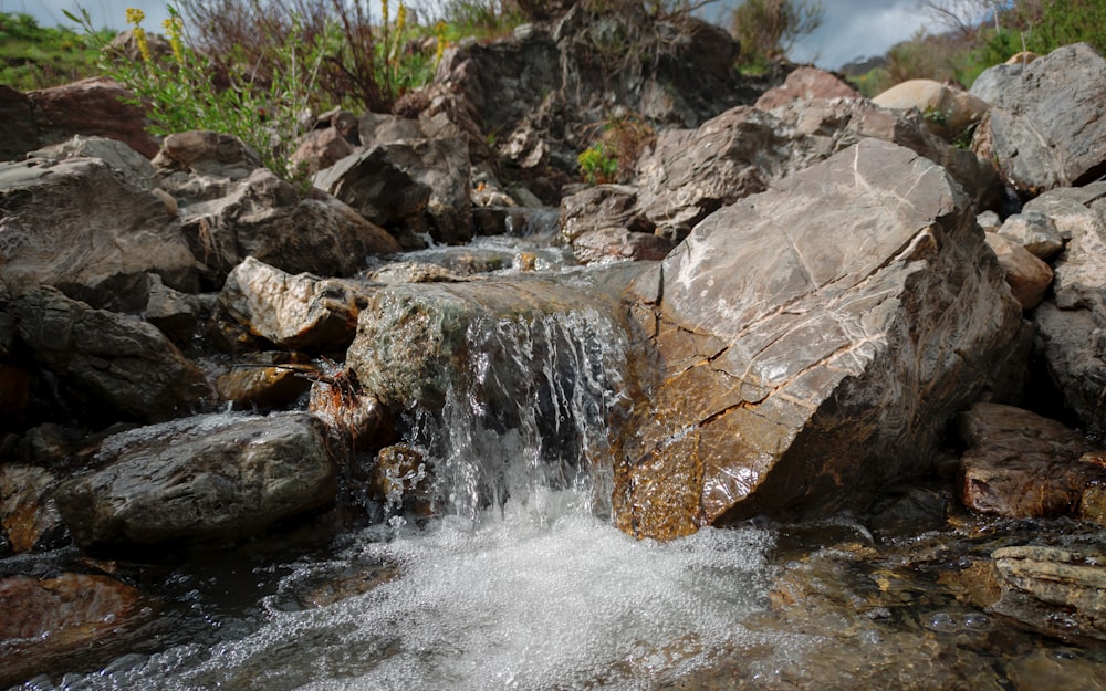 a close up of a small waterfall with rocks in the background