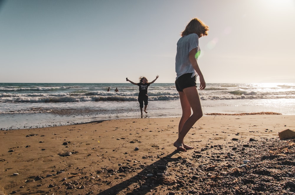 a woman standing on top of a sandy beach next to the ocean