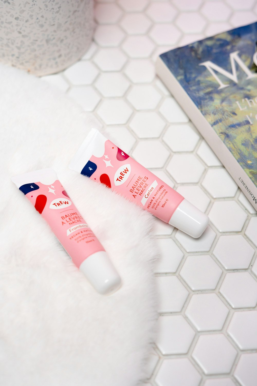 two tubes of lip balm sitting on a table next to a book