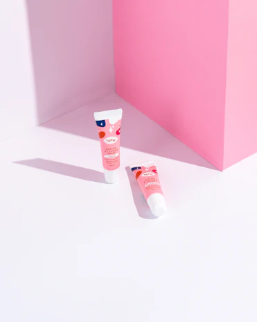 Flat lay of nuné beauty lipcream tubes arranged on a peach-toned background with delicate flowers.