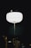 A bright, round street lamp illuminates the surrounding darkness. Small warm lights are visible around it, possibly from decorative string lights on nearby trees. The contrast between the stark white of the lamp and the black background creates a visually striking image.