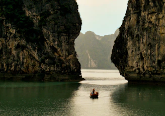 Kayakers paddling through calm waters framed by towering limestone formations.