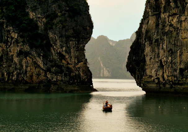 Kayakers paddling through calm waters framed by towering limestone formations.