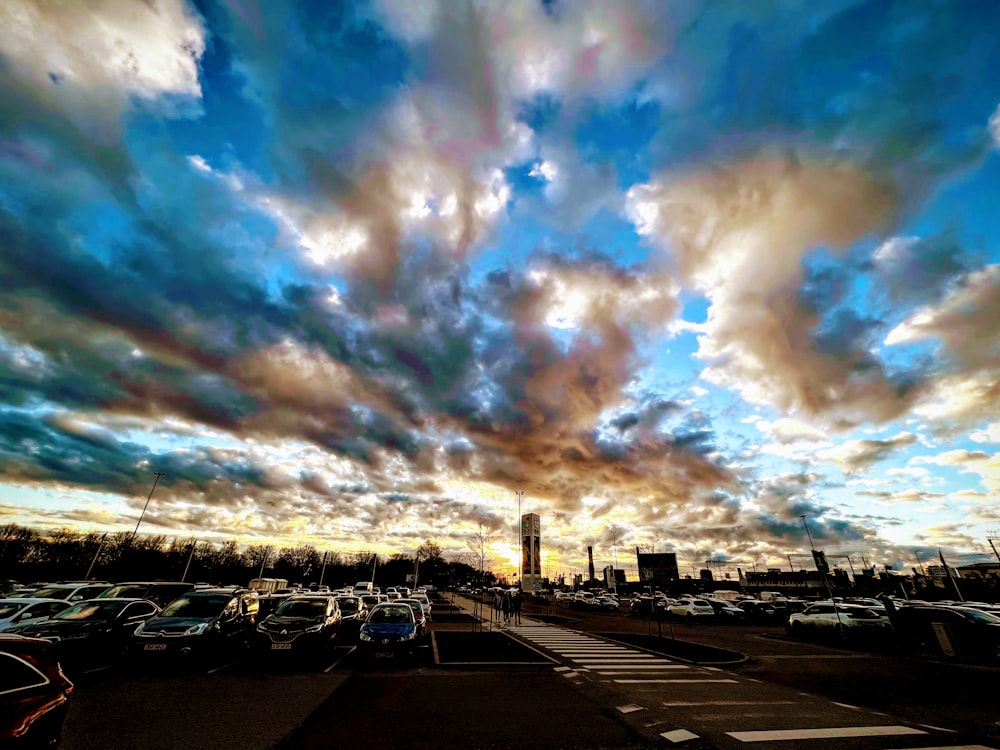 a parking lot filled with lots of cars under a cloudy sky