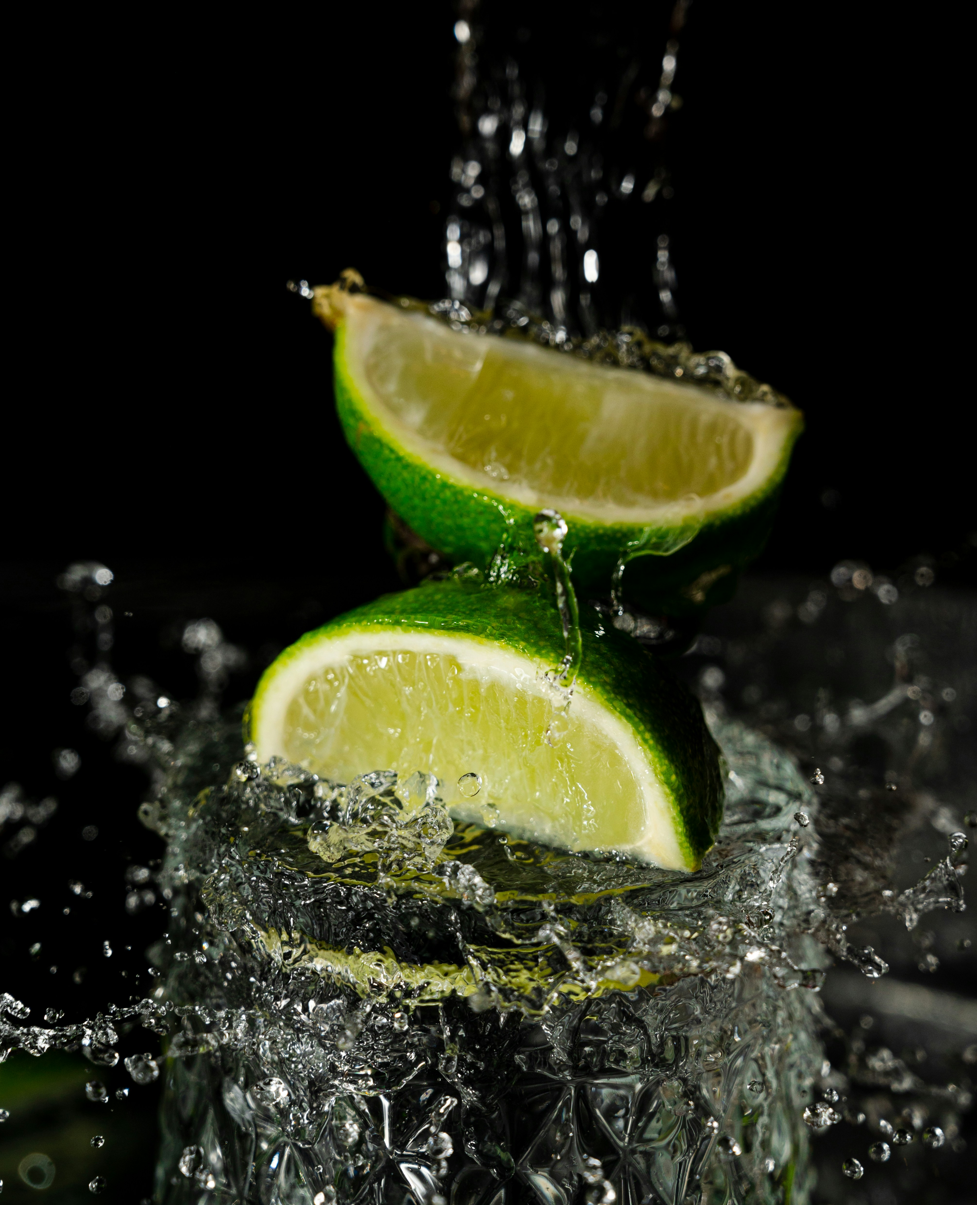 two limes with water splashing on them