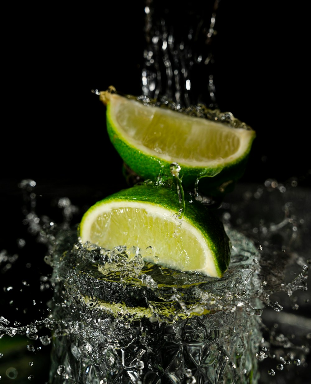 two limes with water splashing on them