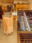 a laptop computer sitting on top of a table next to a drink