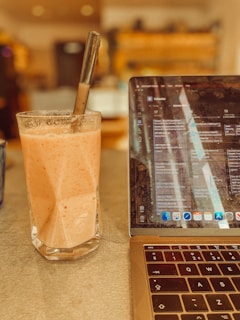 a laptop computer sitting on top of a table next to a drink