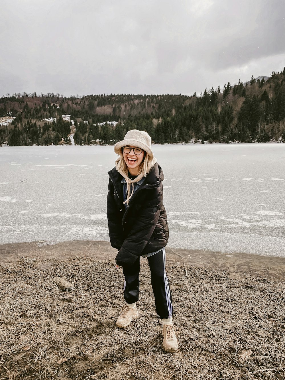 a woman standing on a beach next to a body of water