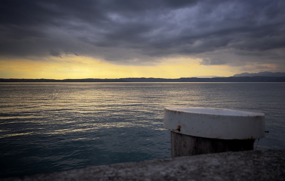 a boat sitting on top of a body of water under a cloudy sky