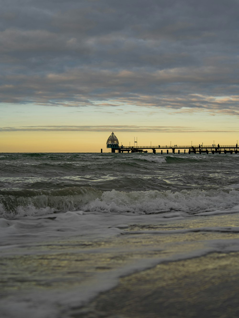 a pier on the ocean with waves crashing in front of it