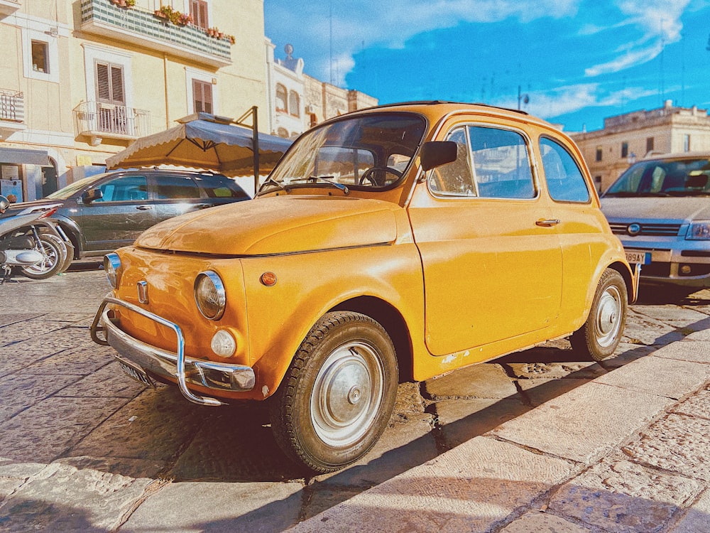 an old yellow car parked on the side of the road