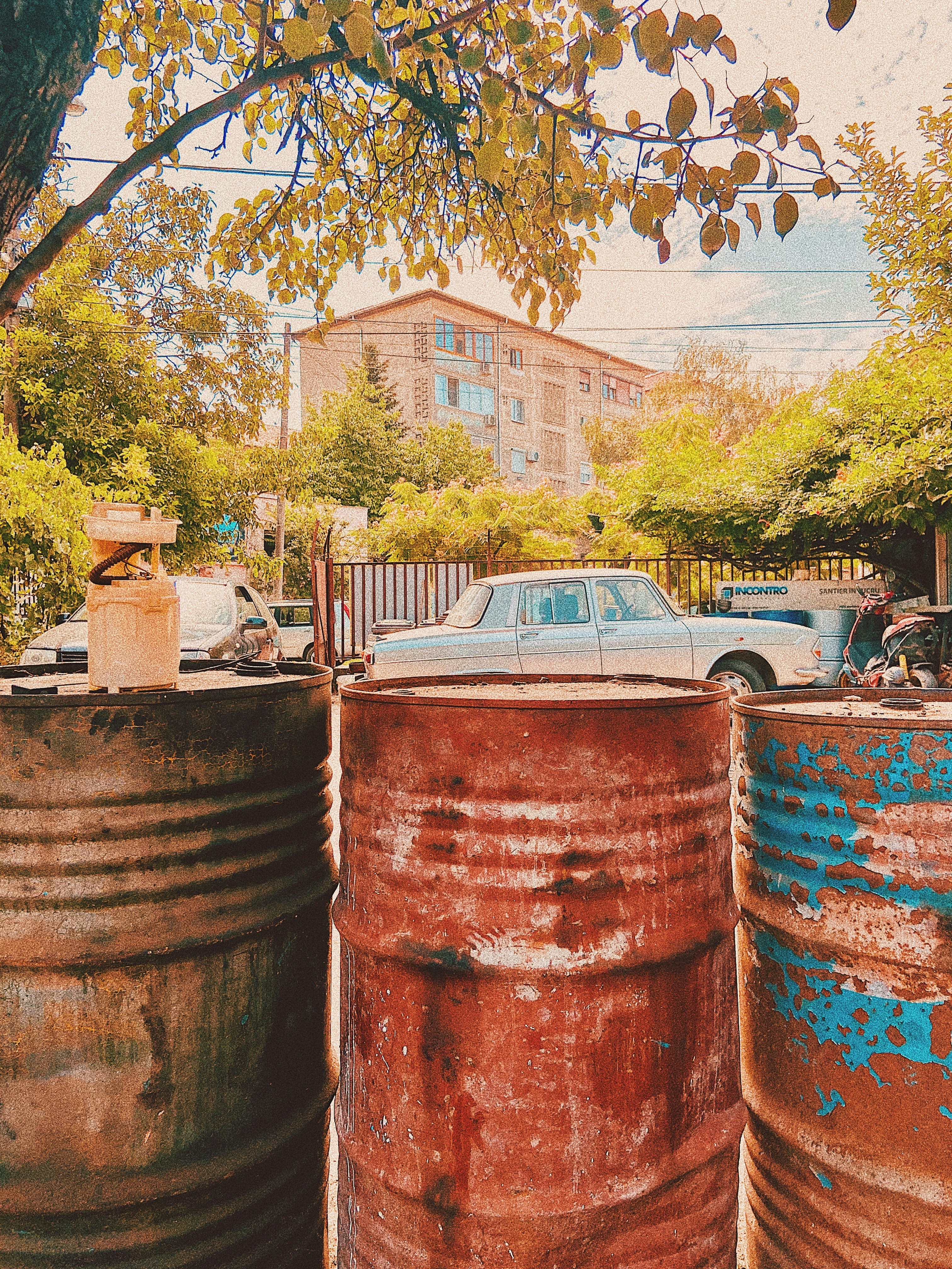 a car is parked in between two rusty barrels