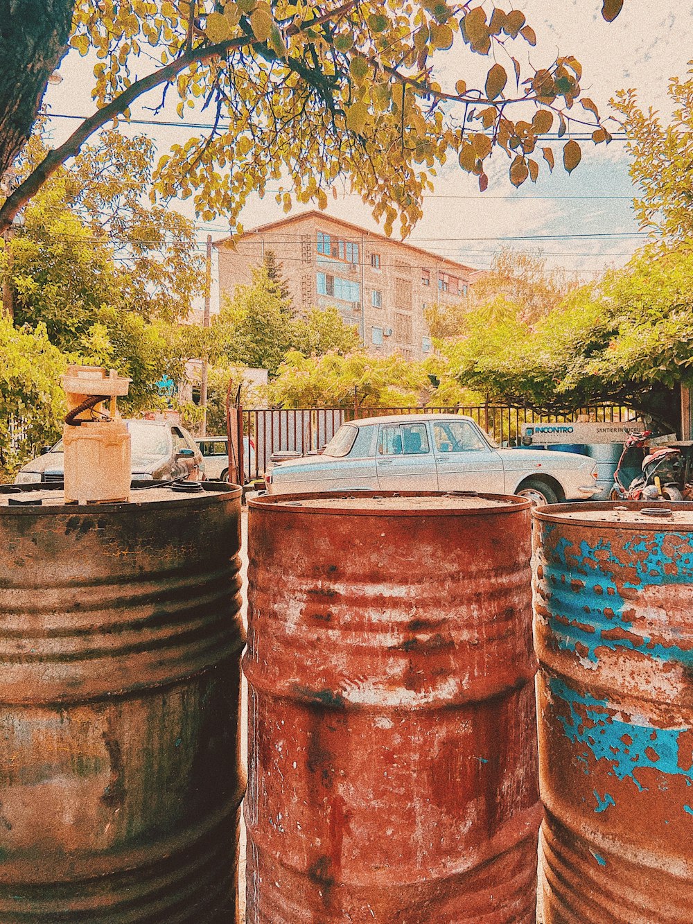 a car is parked in between two rusty barrels