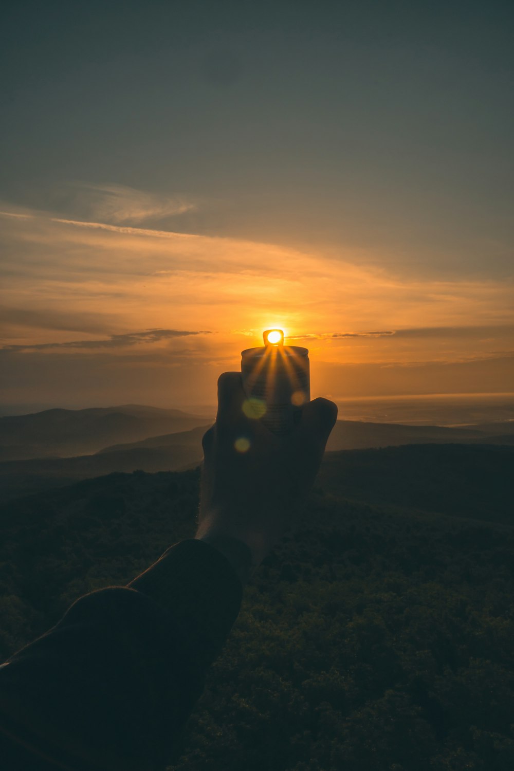 a person holding up a camera with the sun setting in the background