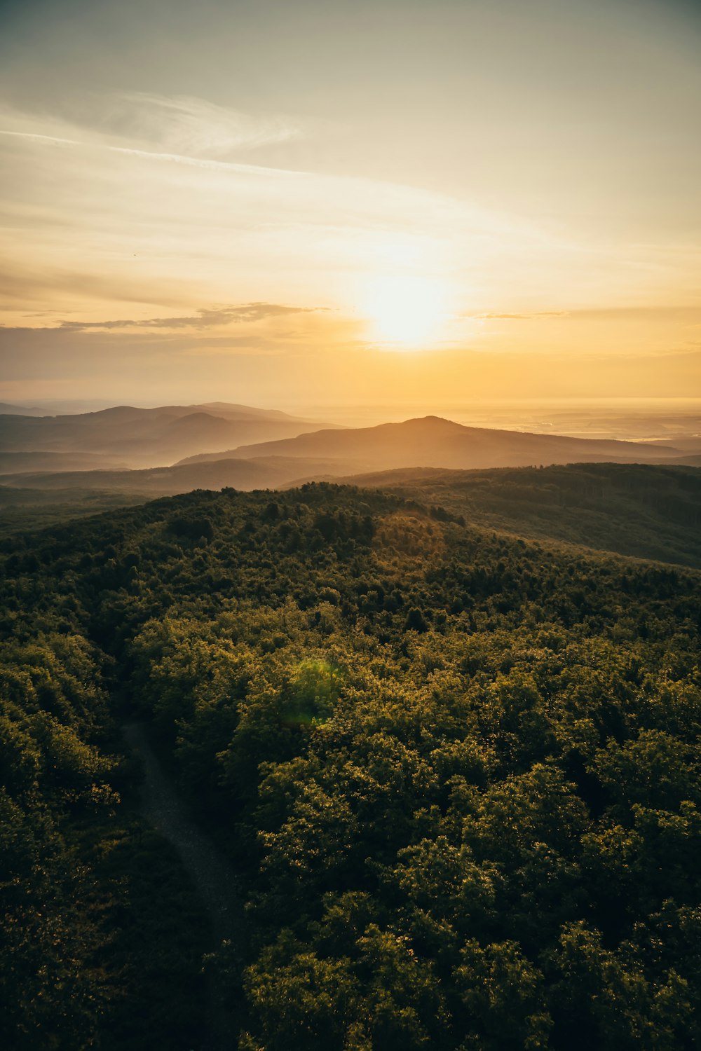 the sun is setting over the hills and trees