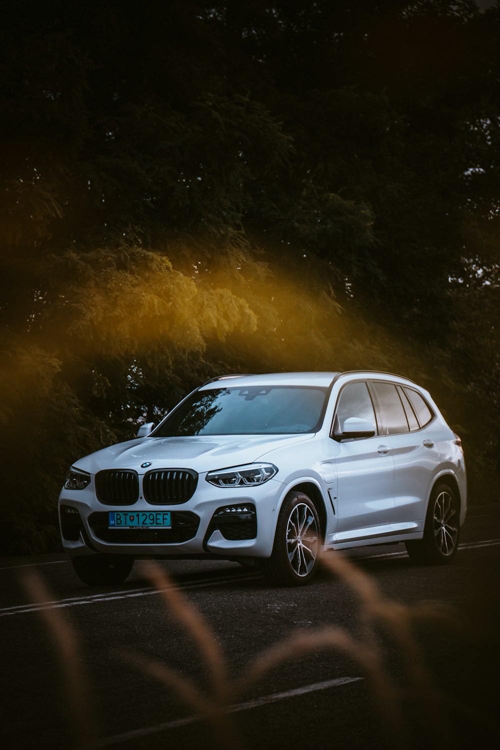 a white bmw suv parked on the side of the road
