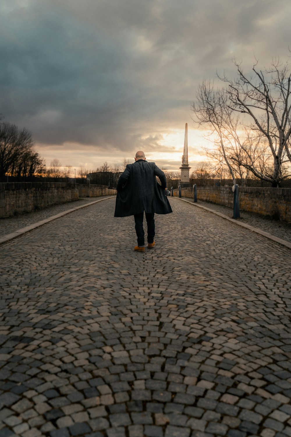 a man walking down a cobblestone road