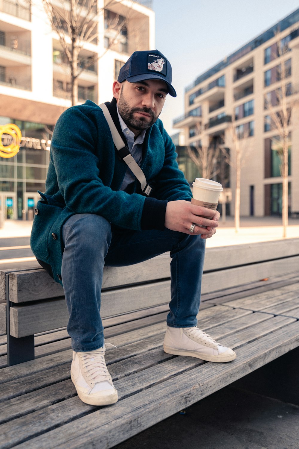 a man sitting on a bench with a cup of coffee