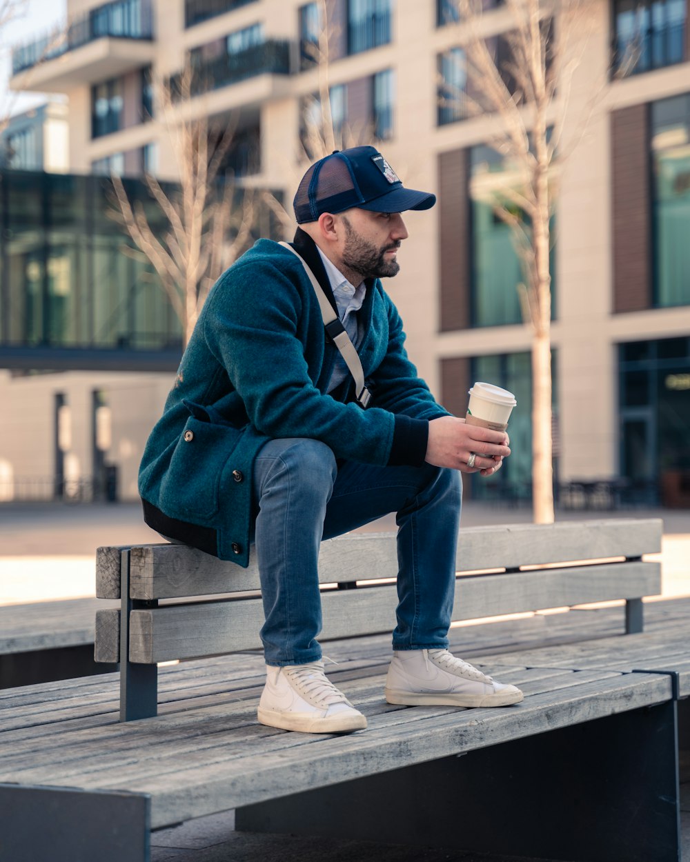 a man sitting on a bench with a cup of coffee