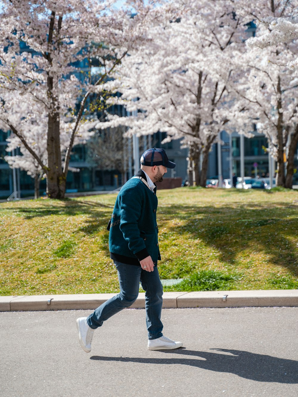 a man walking down the street in front of some cherry blossom trees
