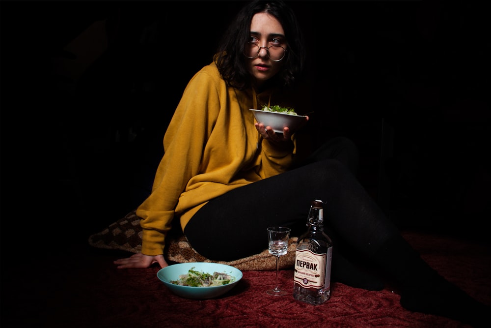 a woman sitting on the floor with a bowl of food